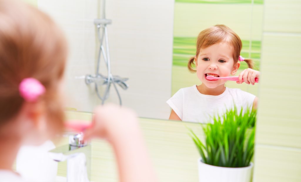 Happy child girl brushing her teeth toothbrushes in bathroom